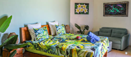 Chambre colorée à la villa Aimehome Teavaro : literie tropicale, climatisation, TV, plantes et vue sur mer