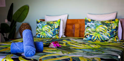 Literie tropicale colorée avec oreillers bleus à la Villa Kia Ora House, Aimehome, Teavaro