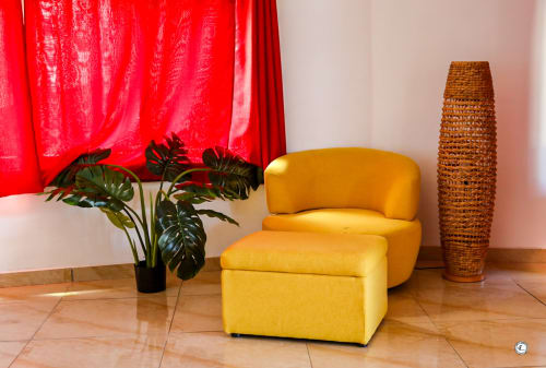 Fauteuil jaune design et ottoman dans le salon de la Villa Kia Ora, avec rideaux rouges et décoration tissée
