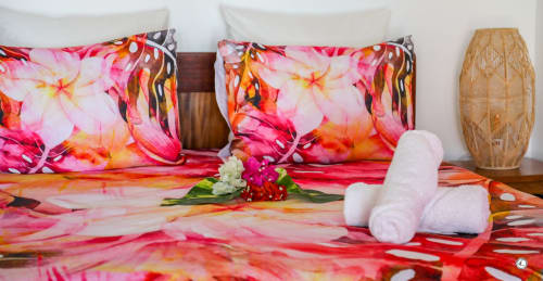 Literie tropicale colorée aux fleurs roses à la villa Aimehome Kia Ora, Teavaro. Serviettes blanches et composition florale sur le lit.