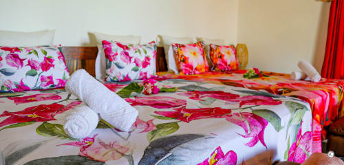 Literie florale éclatante avec serviettes blanches roulées à la Villa Kia Ora House, Aimehome, Teavaro