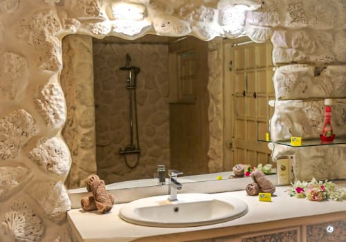 Salle de bain luxueuse de la Villa Kia Ora chez Aimehome, Teavaro, avec murs en pierre, vasque moderne et douche à l'italienne.