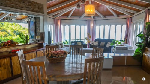 Spacieux espace ouvert de salle à manger et séjour à la Villa Kia Ora avec poutres en bois, vue sur mer et plantes tropicales à Teavaro.