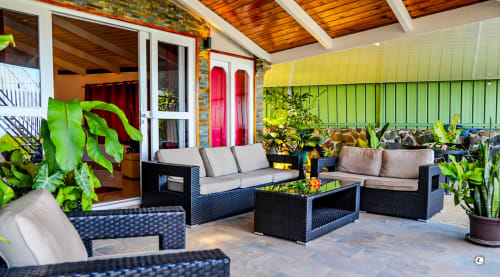 Patio tropical avec mobilier en rotin noir, canapés rembourrés et plantes luxuriantes à la Villa Kia Ora d'Aimehome à Teavaro