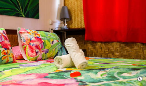 Chambre colorée de la villa Aimehome Moorea avec serviettes roulées sur lit aux motifs tropicaux et décoration vibrante