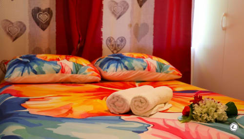 Lit coloré avec serviettes roulées et fleurs à Aimehome, hébergement à Moorea