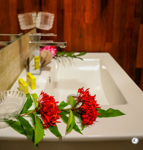 Élégant lavabo de salle de bain orné de fleurs rouges à la villa Aimehome Moorea, avec miroir et accessoires de décoration