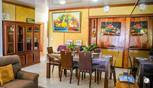 Salle à manger avec meubles en bois et murs jaunes à la villa Aimehome Moorea, table de repas et décoration tropicale