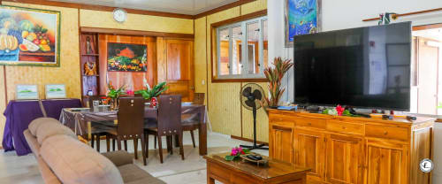 Grand séjour de villa à Moorea avec salle à manger, TV écran plat, mobilier en bois et vue sur l'océan
