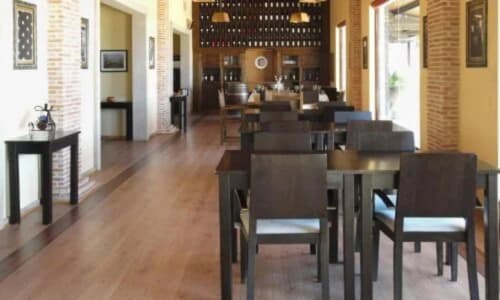 Sala de jantar elegante da adega Tranca da Barriga em Covilhã com cadeiras de madeira, iluminação aconchegante e tijolos rústicos