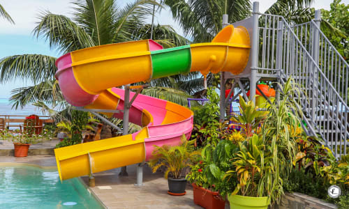 Toboggan aquatique en spirale colorée à la villa Aimehome à Moorea avec piscine, palmiers et vue océan
