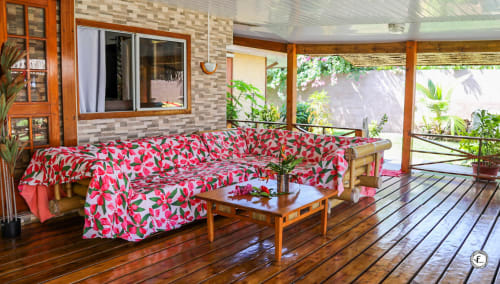 Salon de villa tropicale à Moorea avec canapé à motifs floraux rose, décoration bois et vue sur le jardin
