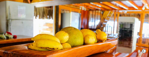 Fruits tropicaux frais exposés sur le comptoir en bois de la cuisine de la villa Aimehome, Moorea