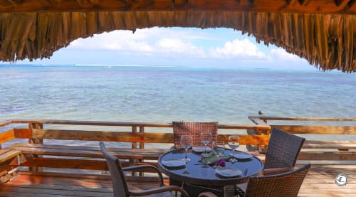 Villa en bord de mer à Moorea avec vue sur la mer turquoise, terrasse en bois et table dressée sous un toit de chaume