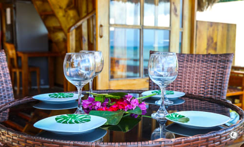 Élégante mise en place en bord de mer à la villa Aimehome Moorea avec couverts dressés, verres à vin et fleurs tropicales