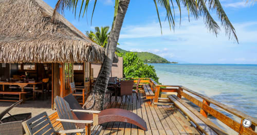 Villa en bord de mer à Aimehome Moorea avec bungalow en paille, terrasse en bois, palmiers et vue sur lagon turquoise