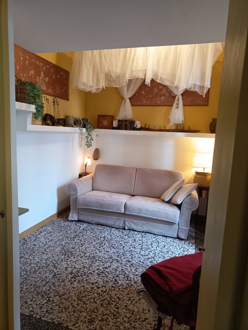 Accogliente salotto della B&B A Casa Armenia a Torino con divano grigio, pareti gialle e arredamento d'epoca