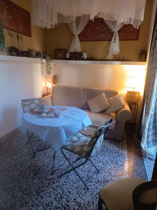 Accogliente soggiorno dell'appartamento Casa Armenia B&B a Torino con posti a sedere, tavolo rotondo, illuminazione calda e arredamento elegante