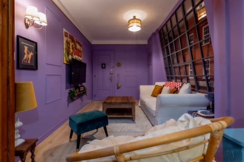 Salon violet de l'hôtel Escape à Pont-à-Mousson avec canapé blanc, pouf turquoise et mobilier bois