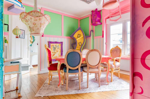 Salle à manger colorée et fantaisiste de l'appartement Au Pays des Merveilles de l'Escape Hotel à Pont-à-Mousson avec des chaises rondes et