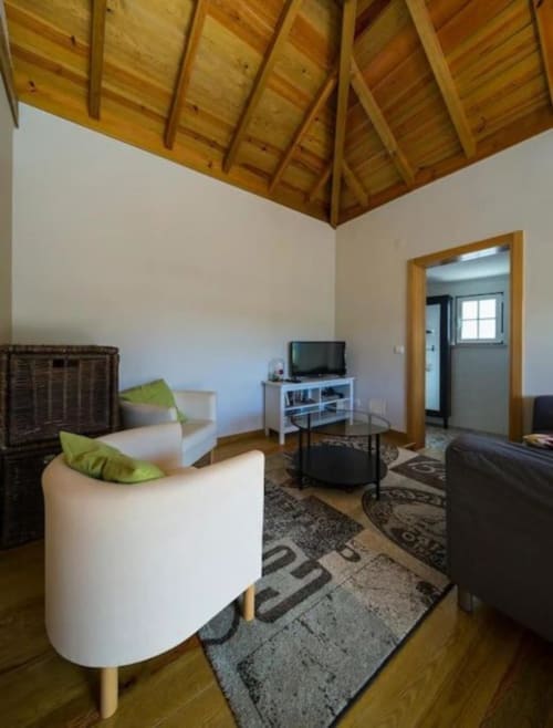 Modern living room at Quinta Boa Vida guesthouse in Alcobaça with exposed wooden beams, comfortable seating, and TV setup