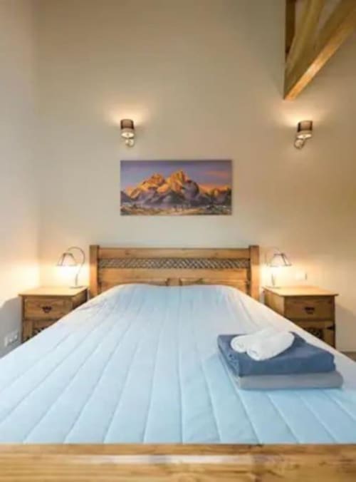 Cozy bedroom at Quinta Boa Vida in Alcobaça with wooden bed, mountain artwork, bedside lamps, and light blue linens