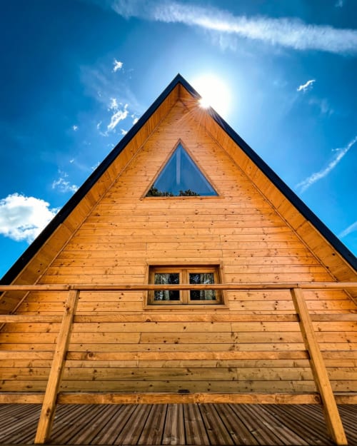 Moderna baita in legno con struttura a capanna e finestra triangolare sotto cielo azzurro, Guarda Che Luna Home & Relax a Sasso di Castalda, Italia