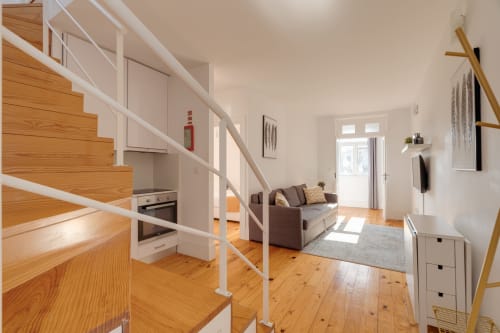 Apartamento moderno no Porto com escadas de madeira, cozinha aberta, sala de estar e muita luz natural