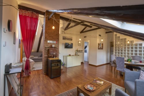 Ampio loft in A Casa Armenia B&B a Torino con travi a vista, pavimenti in legno, tende rosse e servizi moderni