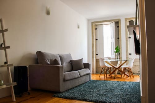 Sala de estar moderna no Bom Porto Apartments com sofá cinzento, tapete azul e vista da área de refeições no Porto