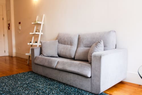 Sofá estofado cinzento com almofadas na sala de estar moderna do Bom Porto Apartments, Porto