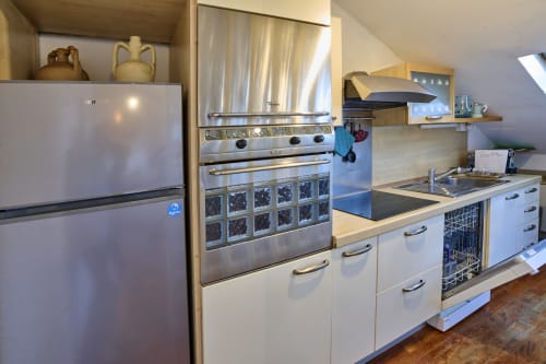Cucina moderna in appartamento torinese con elettrodomestici in acciaio inossidabile, armadi bianchi e zona pranzo