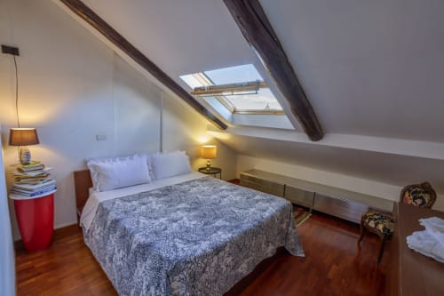 Accogliente camera in soffitta presso A Casa Armenia B&B a Torino con lucernario, travi in legno, letto queen e vista sulla città