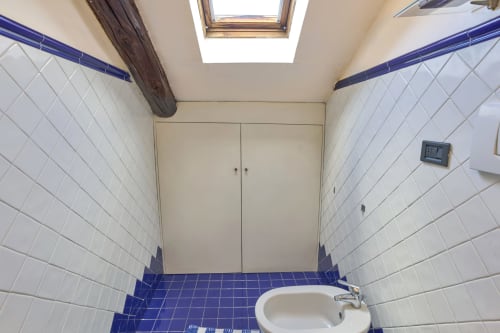 Bagno luminoso con piastrelle bianche, bordi e pavimento blu presso la Casa Armenia B&B a Torino