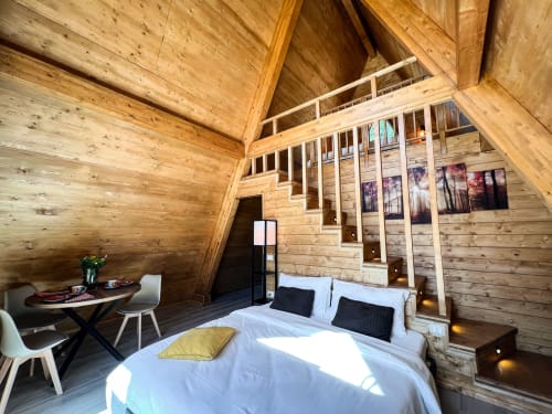 Wooden A-frame glamping room with queen bed, dining area, and mountain views in Sasso di Castalda