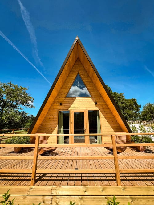 Modern A-frame glamping cabin with wooden deck at Guarda Che Luna in Sasso di Castalda, Italy, surrounded by mountains and