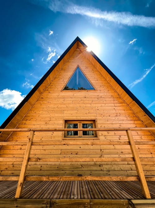 A-Frame Family Glamping cabin at Guarda Che Luna in Sasso di Castalda with wooden exterior and triangular window against blue