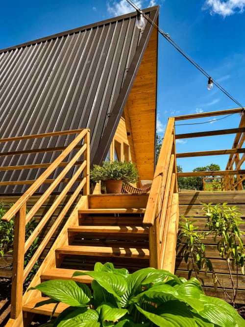 Modern A-frame glamping cabin with wooden deck stairs and metal roof at Guarda Che Luna in Sasso di Castalda, Italy