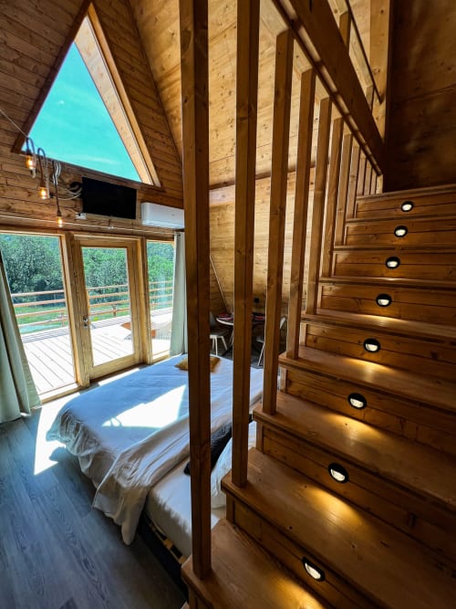 A-Frame Family Glamping bedroom at Guarda Che Luna with wooden beams, bed, dresser, terrace doors, and mountain view in Sasso