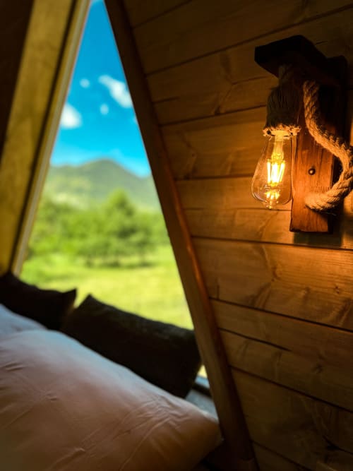 Lantern glow inside A-Frame glamping tent overlooking green mountains at Guarda Che Luna, Sasso di Castalda