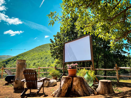 Outdoor glamping area at Guarda Che Luna with Adirondack chairs, screen, and mountain views in Sasso di Castalda
