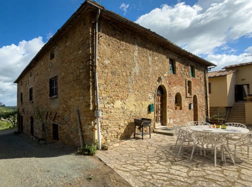Historic stone villa courtyard at Tuscan Sun Stays in Volterra with dining area and arched entrance door