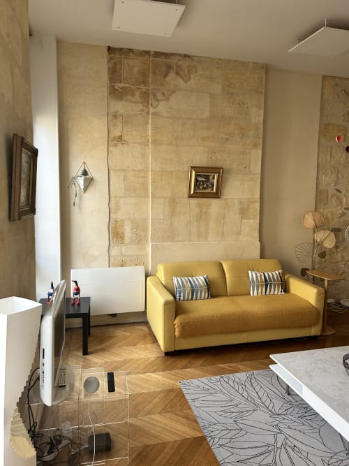 Modern yellow sofa in Dream Properties hotel lounge, La Plagne Tarentaise, with travertine walls and herringbone flooring