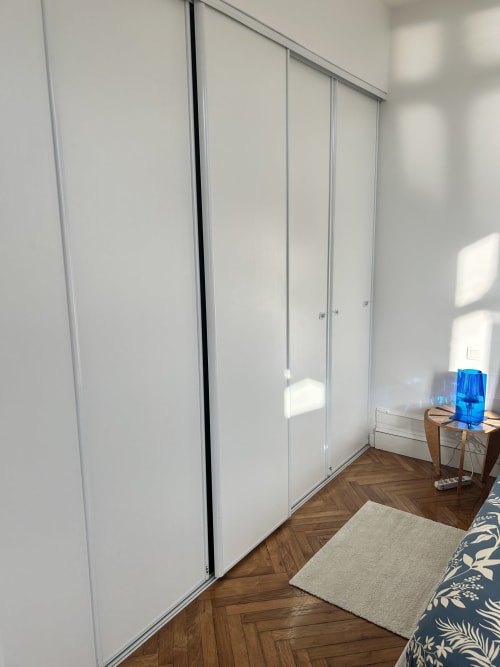Modern bedroom with white sliding wardrobe doors, wooden herringbone flooring, and alpine views at Dream Properties, La