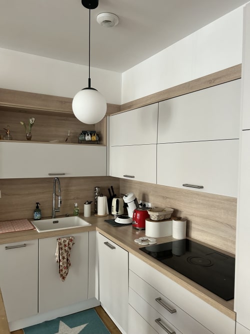 Modern kitchen with white cabinets, wood countertop, black stovetop at Dream Properties, La Plagne Tarentaise