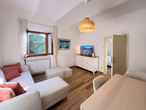 Modern apartment in Volterra featuring white furniture, wooden floors, radiator, pendant light, and views of Tuscan