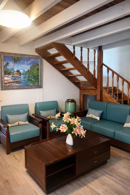 Salon moderne de la Villa Vaipipiha, Aimehome Paopao avec mobilier turquoise, escalier en bois, fleurs tropicales et vue mer