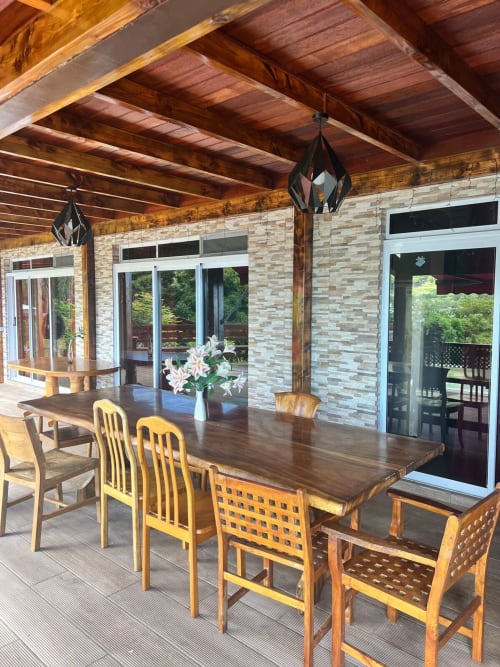 Salle à manger de Villa Vaipipiha avec poutres en bois, fleurs tropicales et portes donnant sur la mer à Paopao, Polynésie française