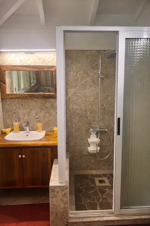Salle de bain moderne à la Villa Vaipipiha chez Aimehome Paopao : vanité en bois, douche en marbre et miroir décoratif