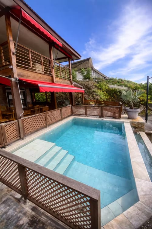 Villa Vaipipiha Aimehome à Paopao avec piscine étincelante, chaises longues et auvents rouges